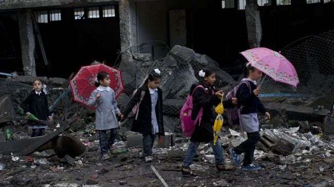 Palestinian schoolchildren walk in debris by a damaged school in Gaza City, Saturday, Nov. 24, 2012.