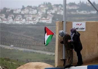 A protester holds the Palestinian flag with the Jewish settlement of Halamish seen in the background during clashes between stone-throwing protesters and Israeli soldiers in Nabi Saleh, near Ramallah on Dec. 21.