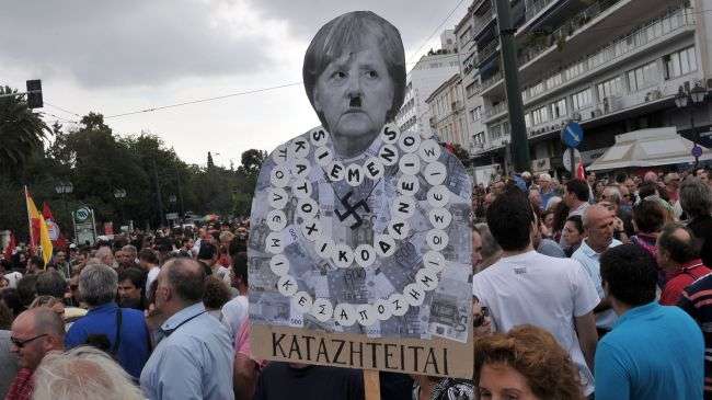 A protester holds a placard of German Chancellor Angela Merkel featuring a Hitler moustache near the Greek parliament in Athens on October 9, 2012.