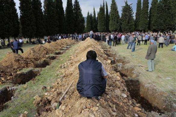 A man sits near graves during the funeral of a miner who died in a fire at a coal mine, at a cemetery in Soma, a district in Turkey western province of Manisa May 14, 2014.