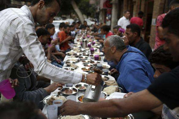 People eat iftar the breaking of fast meal served for free on charity tables on a street during the first day of the holy month of Ramadan in Cairo June 29 2014.