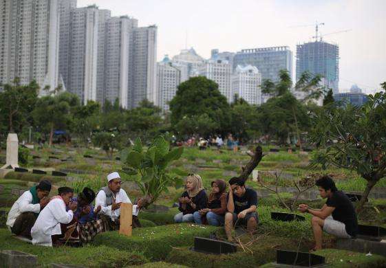 A family reads the Quran at a relative grave in a cemetery in Jakarta Indonesia June 27 2014. Traditionally Indonesian Muslims will visit the graves of their relatives before and towards the end of the holy month.