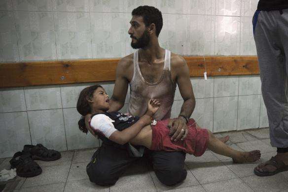 A Palestinian man holds a girl, whom medics said was injured in an Israeli shelling at a U.N-run school sheltering Palestinian refugees at a hospital in the northern Gaza Strip July 24, 2014.