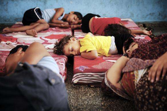 Palestinians sleep at a United Nations school where people who fled heavy Israeli shelling in the Shejaia neighborhood sought refuge during fighting in Gaza City July 21 2014.