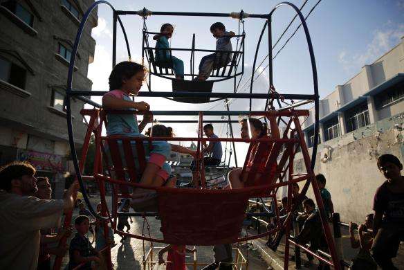 Palestinian children play on a mini Ferris wheel along a street in Beit Lahiya in the northern Gaza Strip July 29 2014.