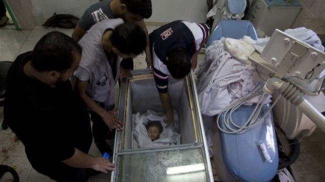 Palestinians gather around the body of a baby being stored in a freezer previously used to store ice-cream because the hospital morgue is full at the Rafah refugee camp, southern Gaza Strip, after she was killed in an Israeli strike, August 4, 2014.