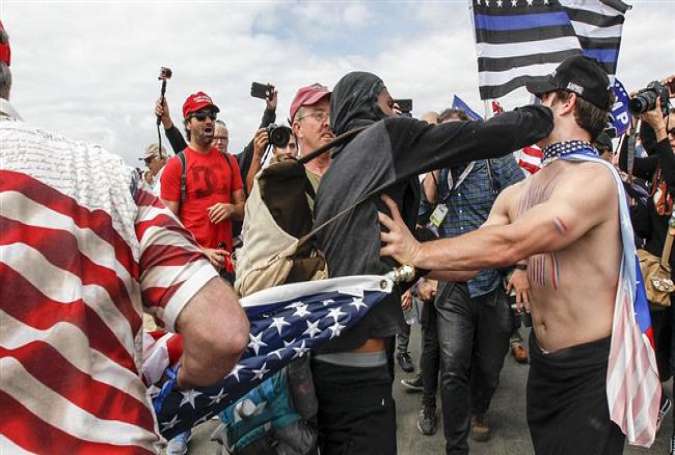 A masked protester pushes a Trump supporter at a MAGA rally in Huntington Beach, March 25, 2017. (Credit: Daily Mail)