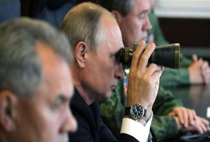 Russian President Vladimir Putin (c) uses a pair of binoculars as he inspects the joint Zapad-2017 (West-2017) Russian military exercises with Belarus at the Luzhsky training ground in Leningrad region on September 18, 2017. (Photo by AFP)