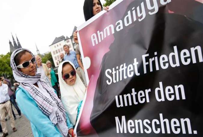 Two girls stand next to a banner citing the Holy Quran and reading “Make peace among the people,” as they take part in a protest rally against terrorism and violence in Cologne, western Germany, on June 17, 2017. (Photo by AFP)