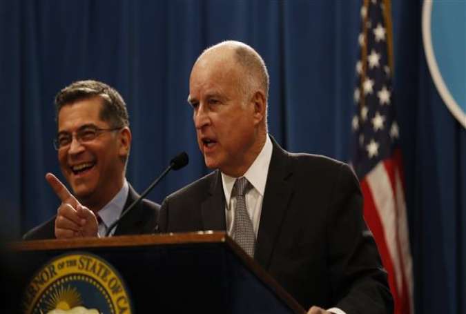 California Governor Jerry Brown gestures as Attorney General Xavier Becerra laughs during a press conference at the California State Capitol on March 7, 2018 in Sacramento, California. (Photo by AFP)