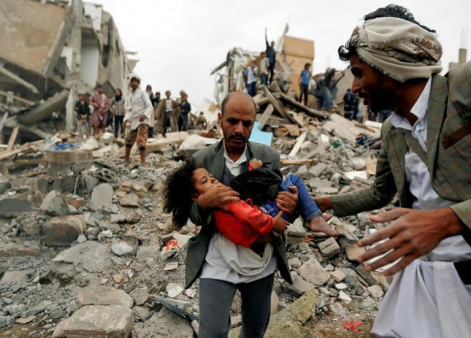 A man carries a child rescued from rubble in the aftermath of a Saudi bombardment of a civilian residence in Yemen