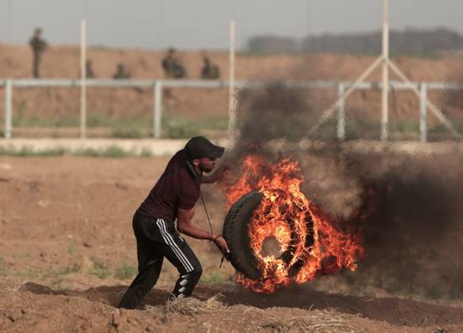 Palestinian throwing a burning tire at the Gaza Strip’s border with occupied territories