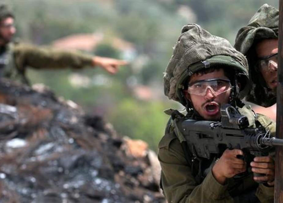 Israeli soldier aims his weapon during clashes with Palestinian protesters.jpg