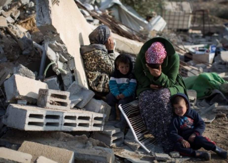 A Palestinian family in front of the ruins of their home in Umm al-Hiran