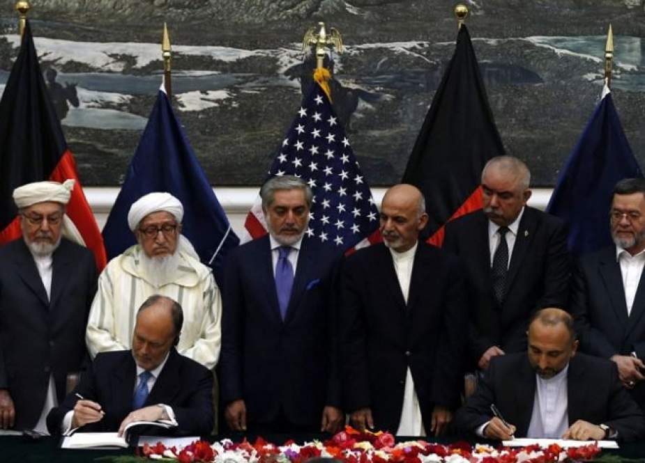 While Afghanistan’s chief executive (4 left) and president (4 right) look on, National security adviser (at table, right) and US Ambassador sign security agreement
