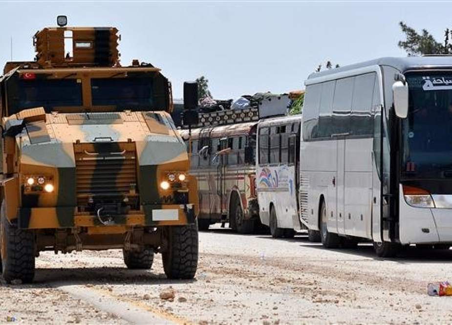 This file photo shows Turkish forces keeping watch as a convoy carries militants and their families from an areas south of Syria
