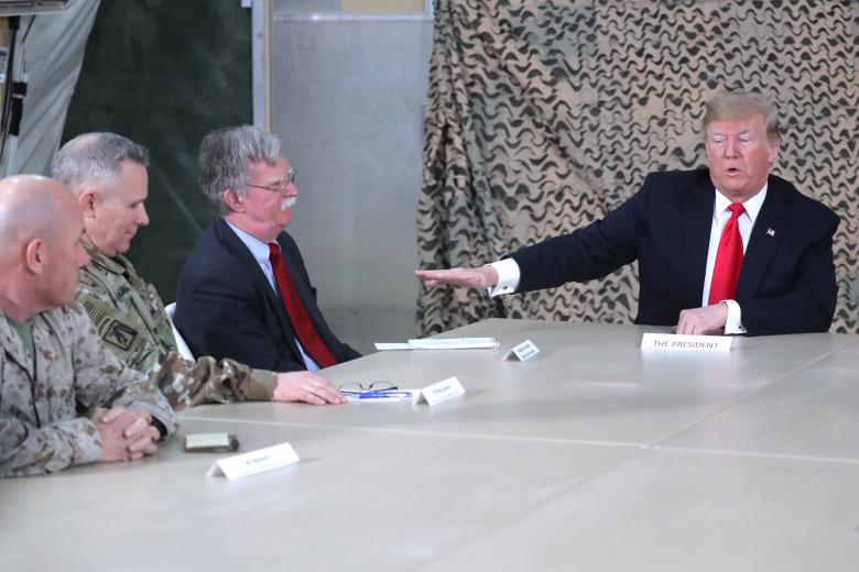 President Donald Trump, flanked by National Security Adviser John Bolton, meets political and military leaders during an unannounced visit to Al Asad Air Base, Iraq.