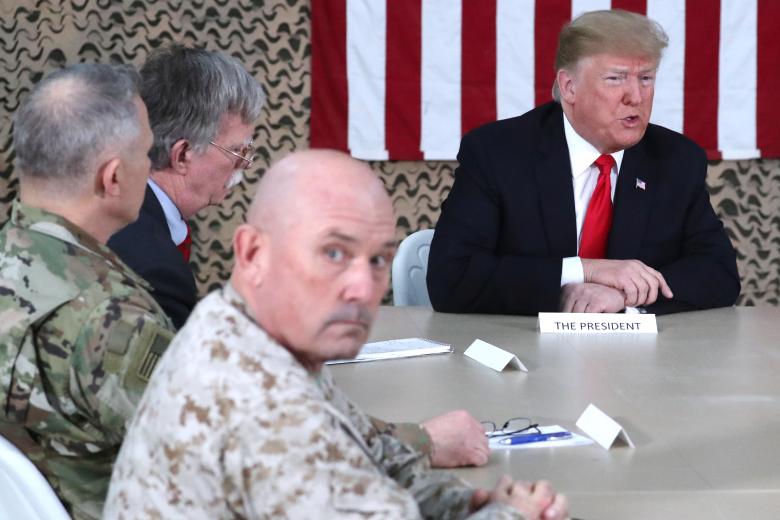 President Donald Trump, flanked by National Security Adviser John Bolton, meets political and military leaders during an unannounced visit to Al Asad Air Base, Iraq.