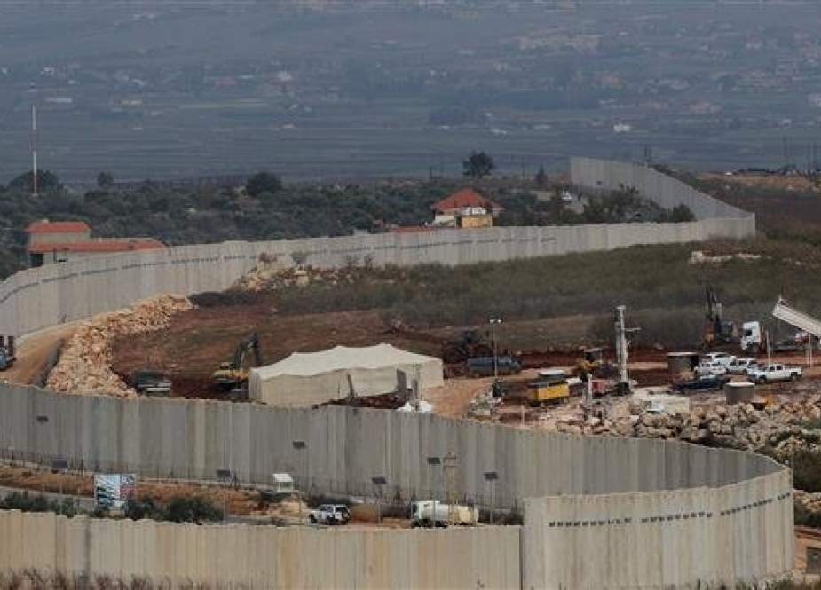 A picture taken on December 16, 2018 from the southern Lebanese village of Adaisseh shows members of the Israeli military, excavators, trailers and other vehicles operating on the Israeli side, behind the wall separating the two countries.