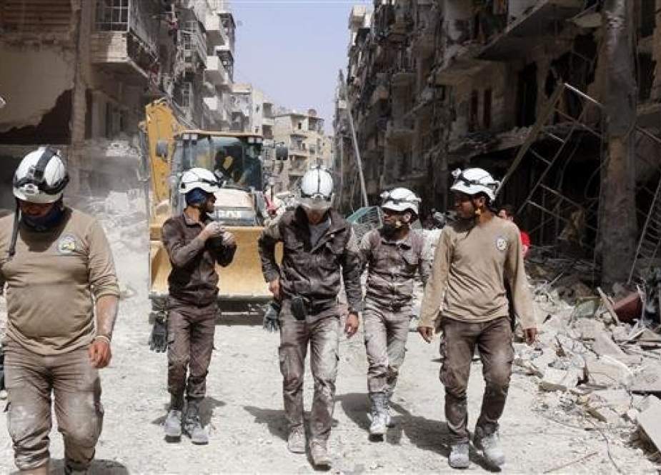 In this file picture, members of the so-called White Helmets group walk amid rubble in an undisclosed location in Syria.