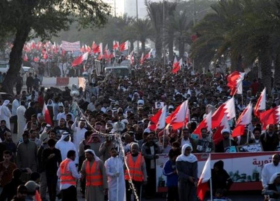 Thousands of Bahraini anti-government protesters chant slogans as they wave national flags during a march in Diraz, Bahrain, January 17, 2014. (By AP)