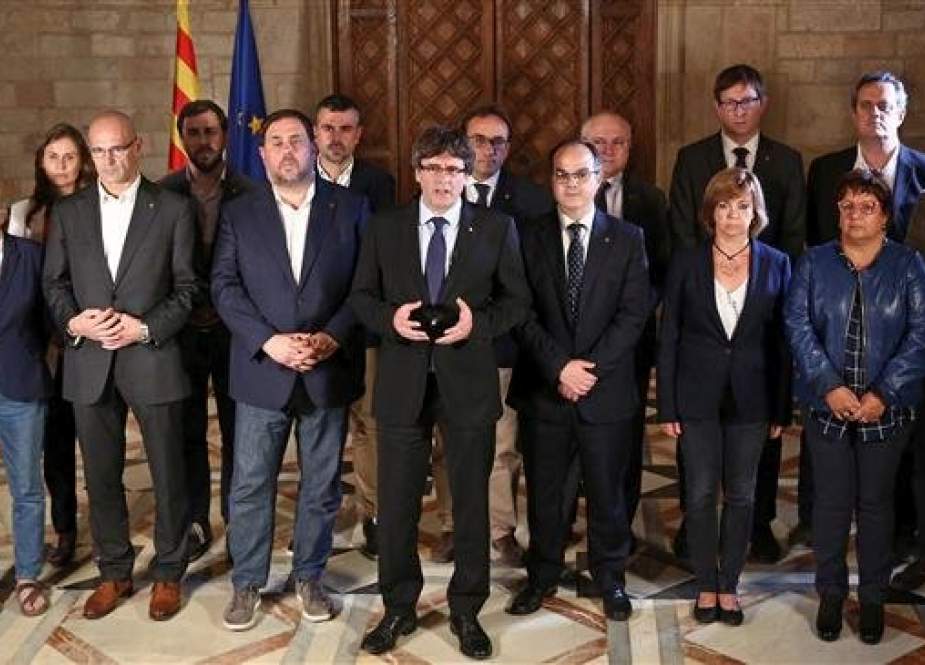 In this file photo, taken on October 1, 2017, then-Catalan president Carles Puigdemont (C) is seen talking to the media next to members of his government in Barcelona, following a referendum on independence for Catalonia banned by Madrid. (By AFP)