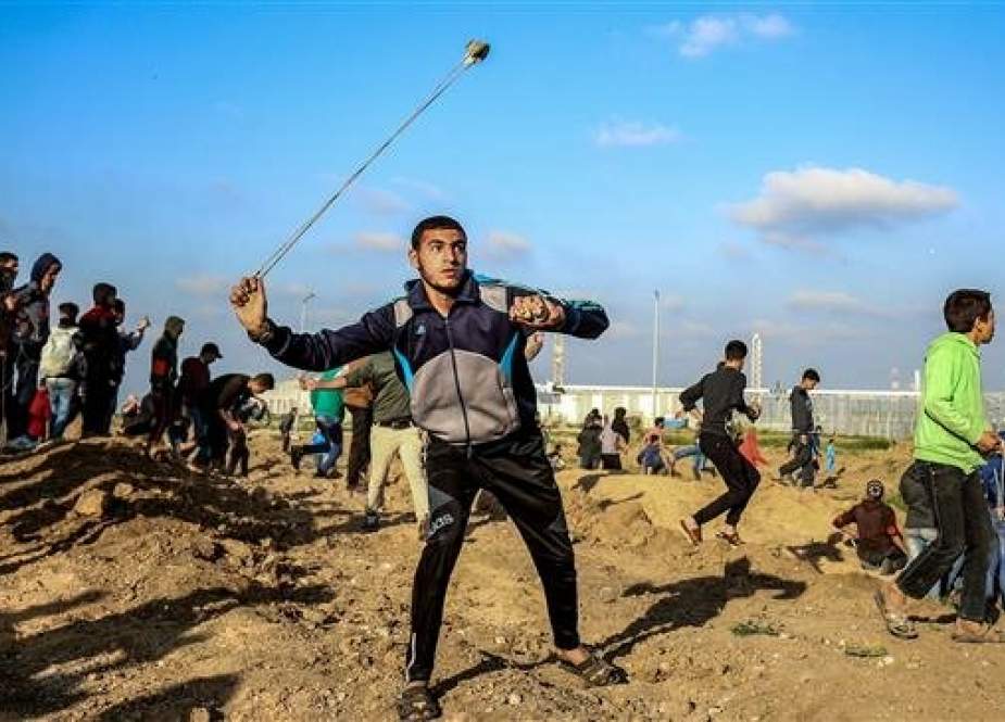 Palestinian protester uses a slingshot to hurl objects during clashes with Israeli forces.jpg
