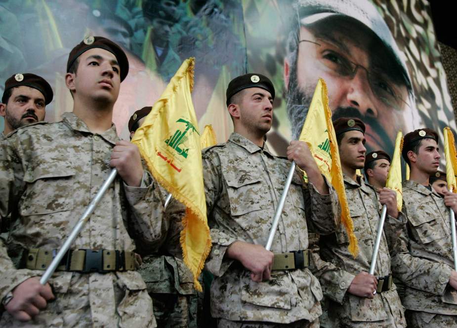 Hezbollah fighters hold their party flags and stand next to a portrait which shows their slain top commander Imad Mughniyeh, as they attend a rally to commemorate Mughniyeh and two other leaders, Abbas Musawi and Ragheb Harb, in the Shiite suburb of Beirut, Feb. 22, 2008.