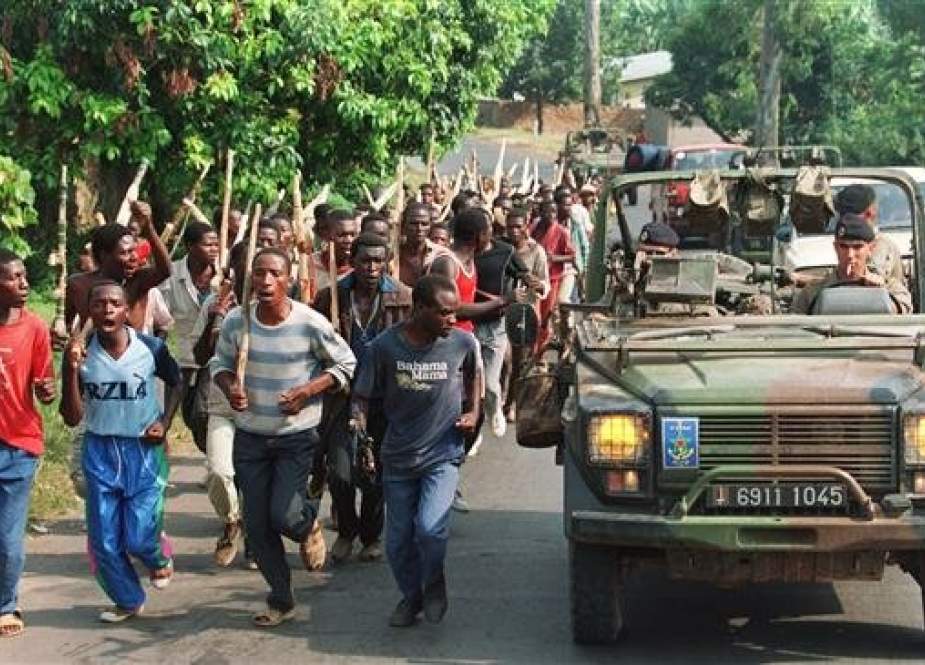 French soldiers patrol past Hutu vigilantees from the Rwandan government forces in 1994.