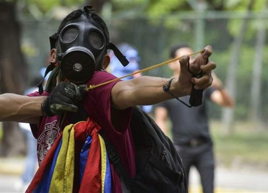 A Venezuelan student uses a slingshot, in clashes with riot police, at a protest in Caracas, on November 21, 2018. (Photo by AFP)