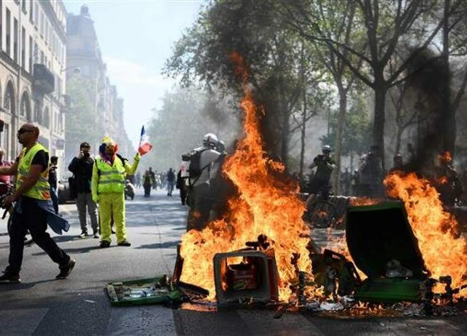 Protesters stand next to a burning barricade during an anti-government demonstration called by the Yellow Vest movement, on April 20, 2019, in Paris. (Photo by AFP)