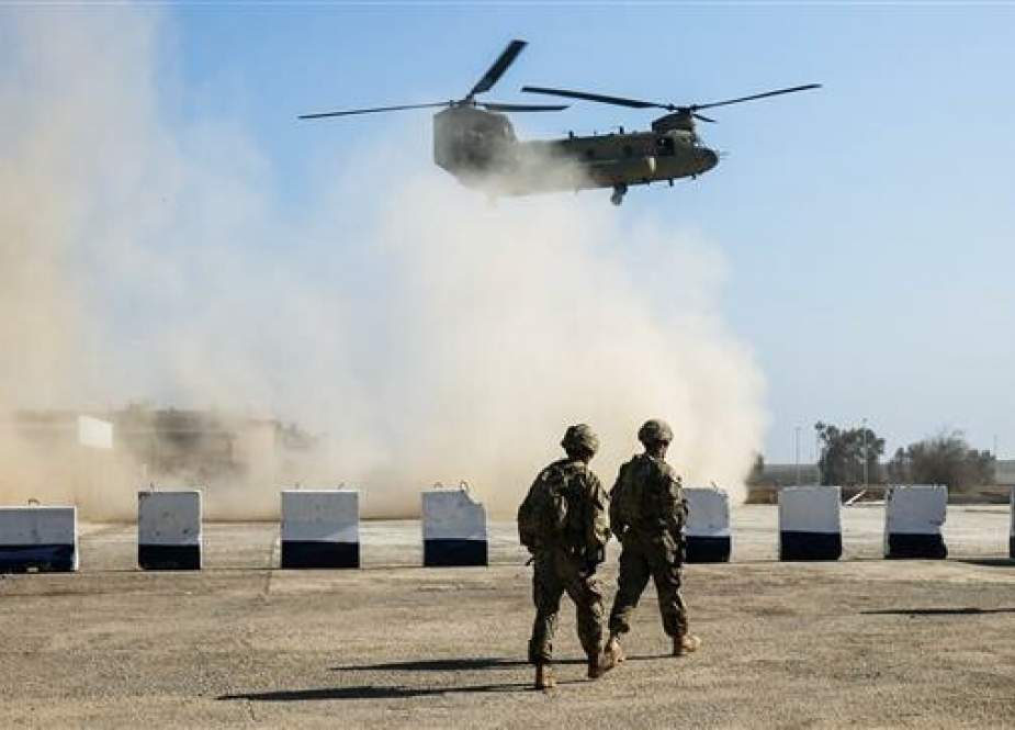 File photo shows US troops patrolling as a US Army C-47 Chinook helicopter flies overhead in Iraq.
