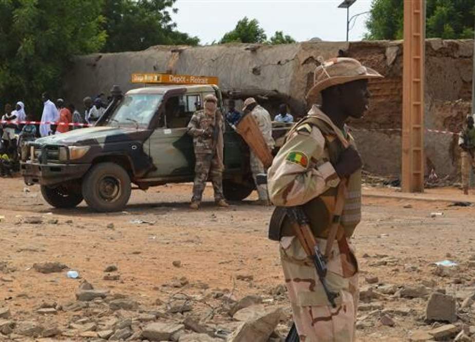 A Malian soldiers stand beside a destroyed building on November 13, 2018, in Gao, after a suicide car overnight, which killed three people. (Photo by AFP)