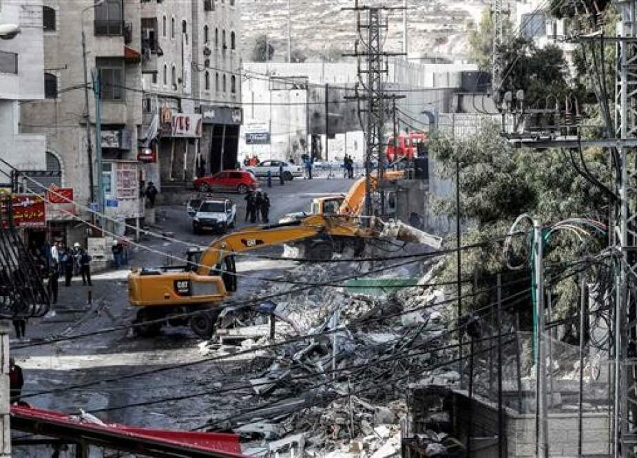 This picture taken on November 21, 2018 shows an excavator of the so-called Municipality of Jerusalem al-Quds demolishing one of over a dozen shops in the Arab-inhabited Shuafat refugee camp in Israeli-occupied East Jerusalem al-Quds, which Israeli authorities said were built without a permit. (Photo by AFP)