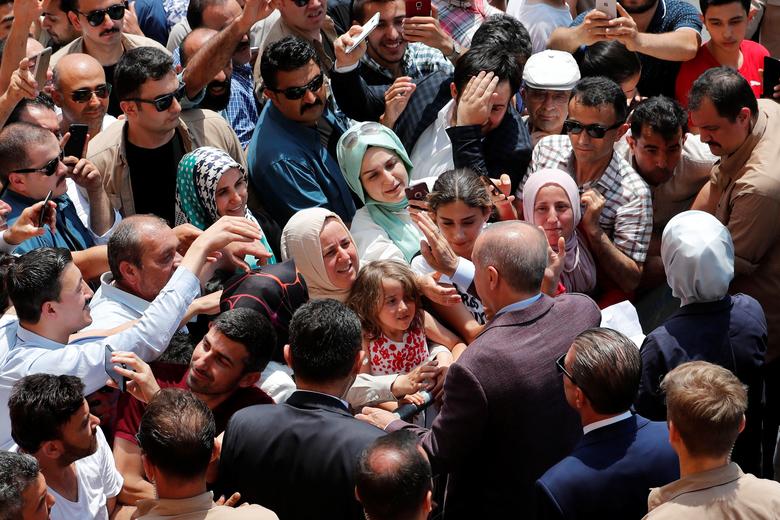 Turkish President Tayyip Erdogan and his wife Emine greet people after casting their ballots, outside a polling station in Istanbul, June 23