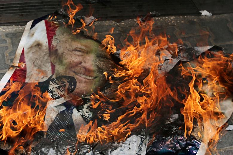 Palestinians burn a poster depicting U.President Donald Trump during a protest against Bahrain's workshop for U.S. Middle East peace plan, in the southern Gaza Strip, June 25