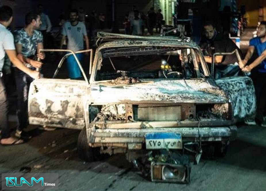A picture taken early morning on August 5, 2019 shows people surrounding a burned car after an accident that caused an explosion leaving 16 dead and 21 injured in downtown Cairo.