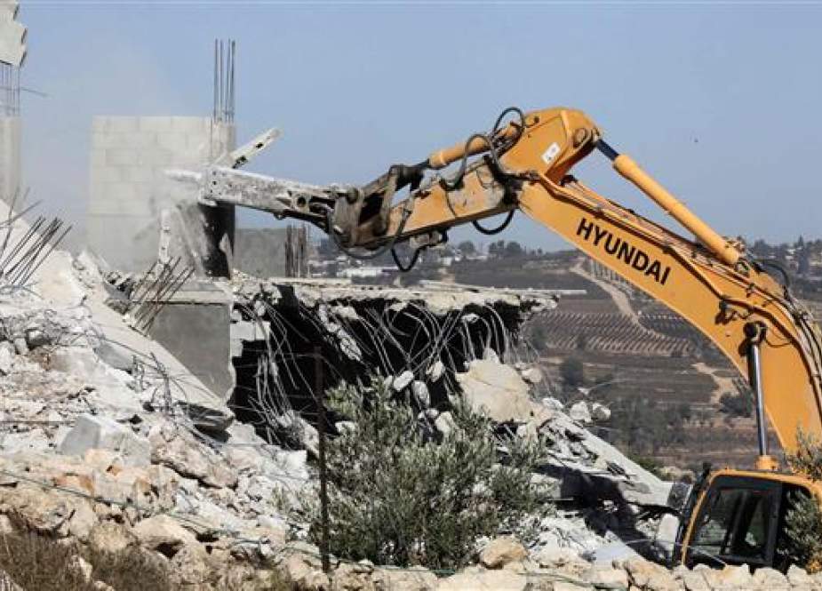 An Israeli bulldozer demolishes a Palestinian shack east of Yatta town in the southern West Bank.jpg