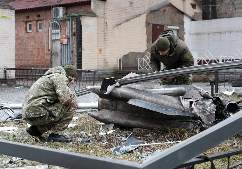 Police officers inspect the remains of a missile that fell in the street in Kyiv, Ukraine, February 24.
