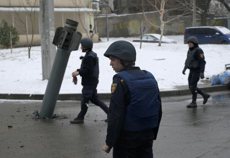 Members of the State Emergency Service of Ukraine walk towards a rocket case stuck on the driveway following recent shelling in Kharkiv, Ukraine February 25, 2022.