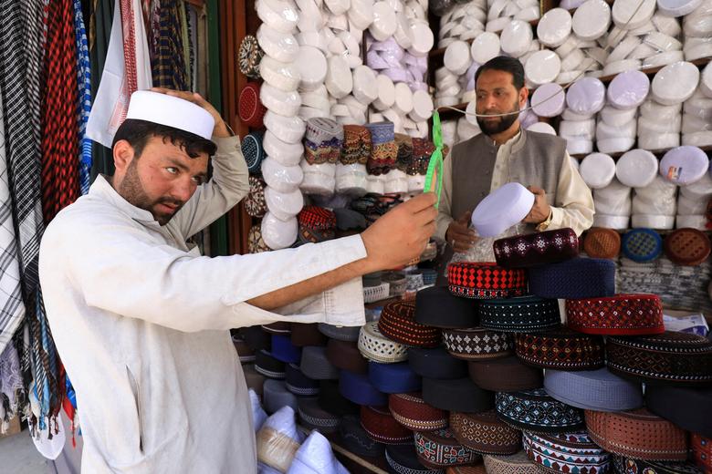 A man checking himself in a mirror while shopping for a cap at a stall outside a mosque to mark the fasting month of Ramadan in Peshawar, Pakistan April 2.