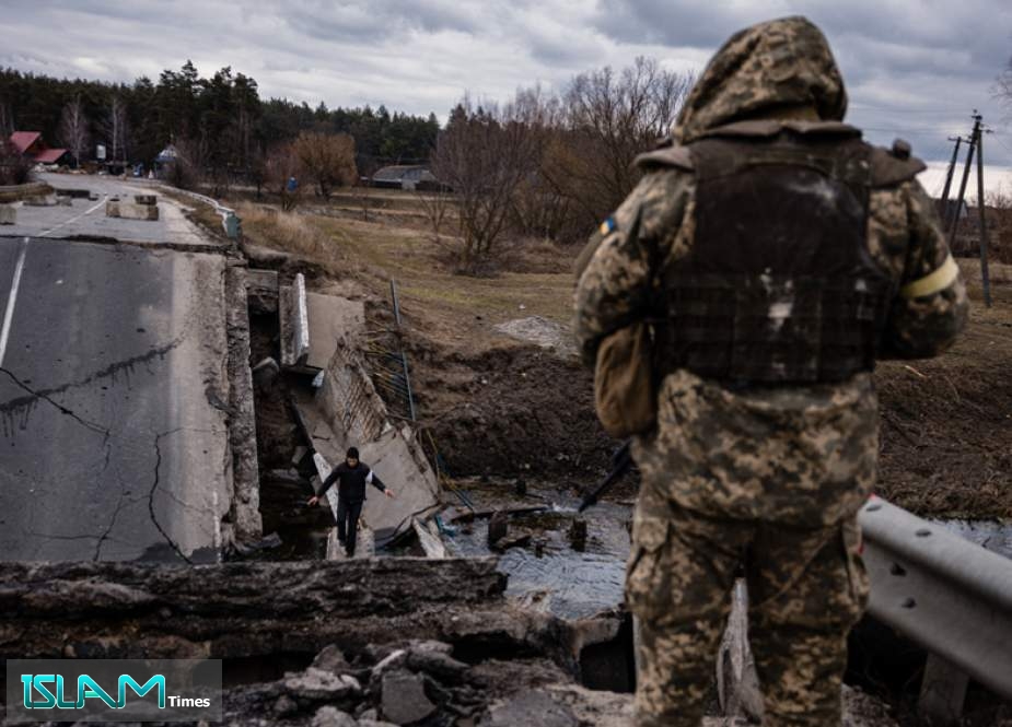 A Ukrainian soldier looks at a civilian crossing a blown-up bridge in a village, east of the town of Brovary, on March 6, 2022.