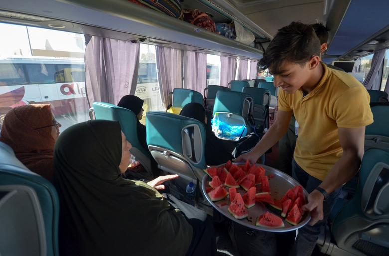 Volunteer Abdulrahman al Maani distributes watermelon to pilgrims leaving for Mecca for Haj, in Maan, Jordan, June 28, 2022.