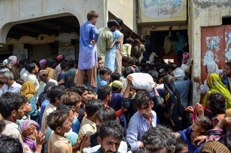 Flood victims gather outside a school to receive ration handouts, following rains and floods during the monsoon season in Dera Allah Yar, Jafferabad District, Pakistan, September 4, 2022.