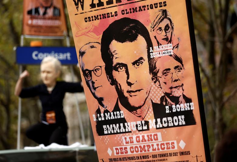A poster with a portrait of French President Emmanuel Macron is pictured next to a protestor wearing a mask depicting Bernard Arnault, chairman of LVMH Moet Hennessy Louis Vuitton, during a demonstration in Paris, October 18.