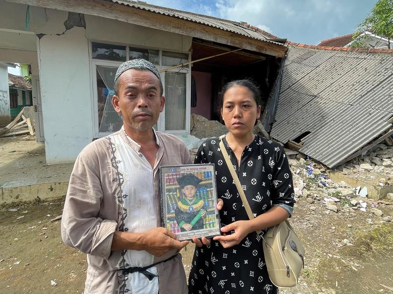 Ujang Nurdin and Rian Solihat, hold a portrait of their daughter Vira Aprilianti, an 8-year-old student who was found dead under the ruins of a Madrasah that collapsed during an earthquake in Cianjur, Indonesia, November 23, 2022.