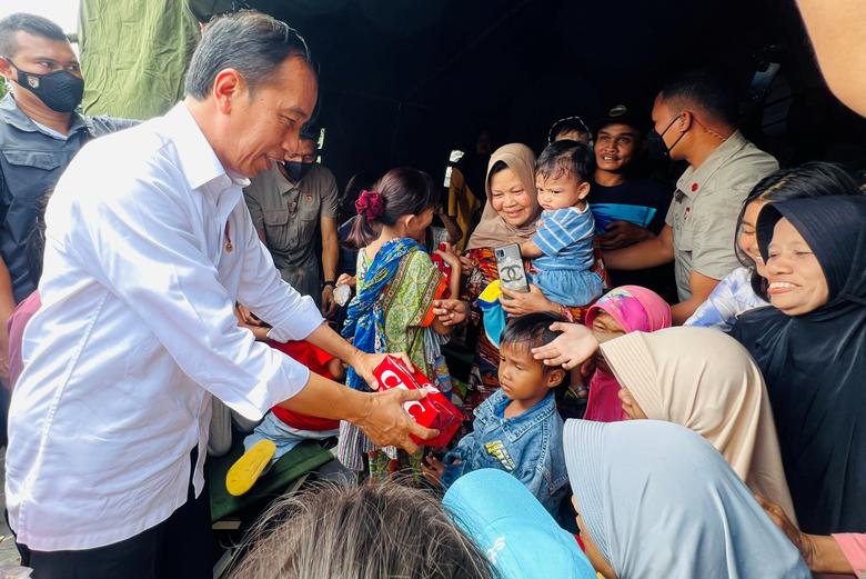 Indonesian President Joko Widodo distributes meals to local children at a temporary shelter during his visit to the locations affected by earthquake in Cianjur, West Java province, Indonesia, November 22, 2022.