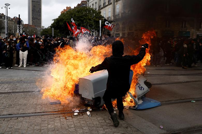 Protesters stand near burning garbage bins during a demonstration against French government's pension reform, in Nantes, France, March 23.  REUTERS/Stephane Mahe