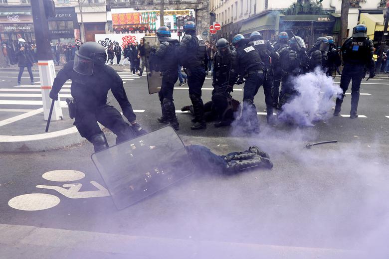 A French police officer in riot gear, injured during clashes with protesters, is given help at a demonstration against French government's pension reform, in Paris, France, March 23.  REUTERS/Gonzalo Fuentes