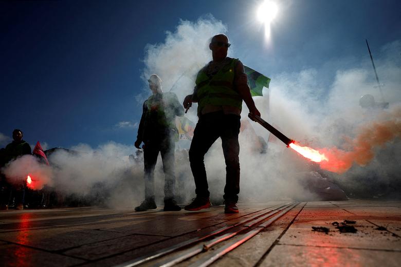 Workers on strike hold flares during a demonstration in front of the railway station after the pension reform was adopted as the French Parliament rejected two motions of no-confidence against the government, in Nice, France, March 22.   REUTERS/Eric Gai